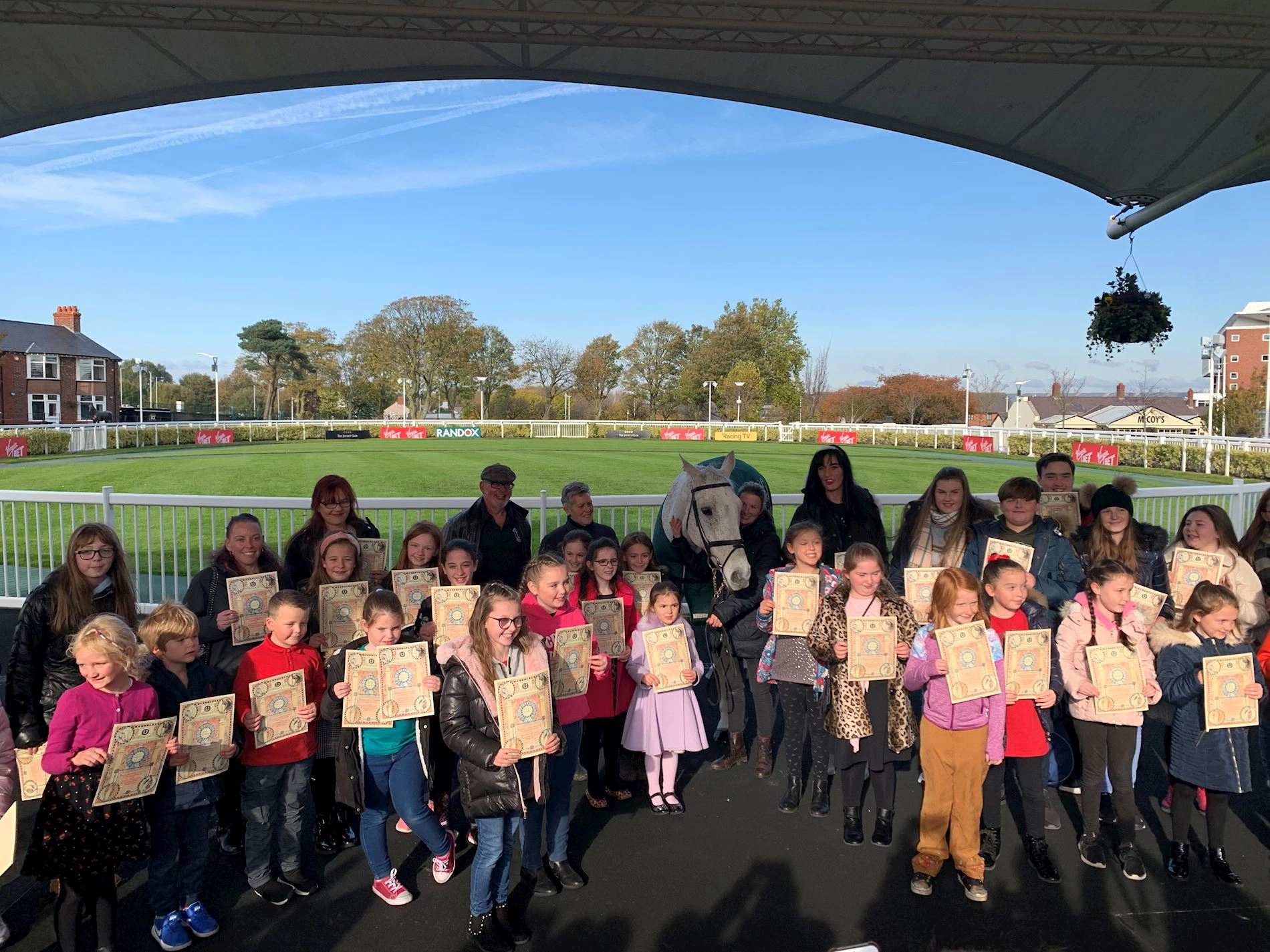 A group of school children in the Aintree Parade Ring with Grand National winning horse, Neptune Collonges.