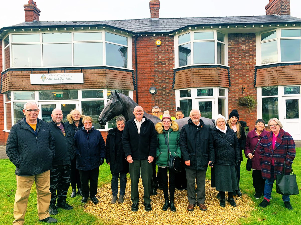 A group of people standing outside the Community Hub at Aintree Racecourse